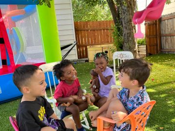 Four children smiling and talking outdoors.