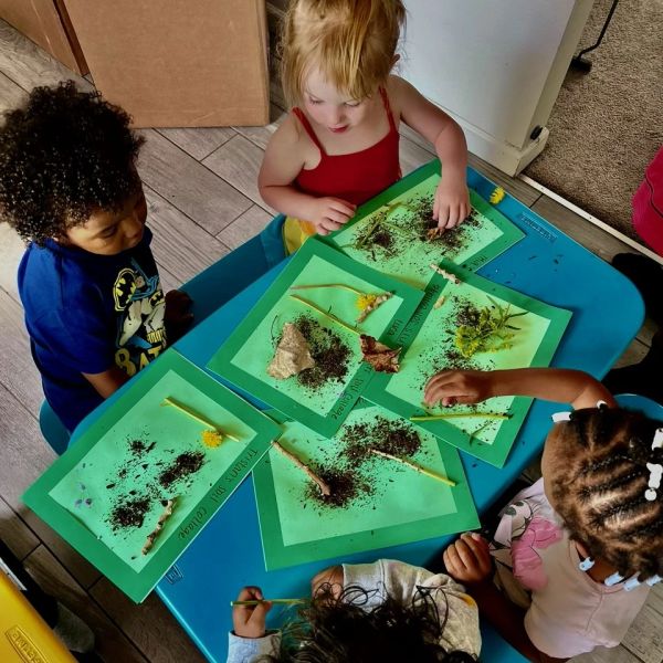 Children exploring nature at a blue table.