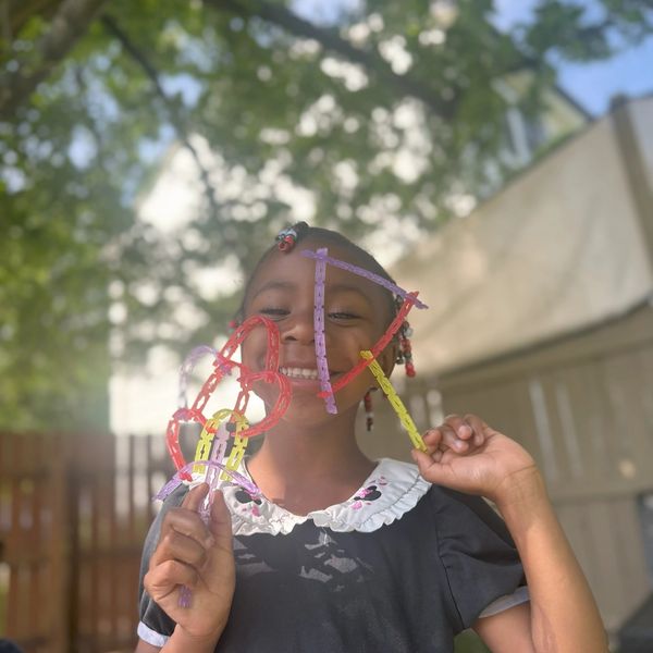 Girl smiling with colorful toy in the sunlight.