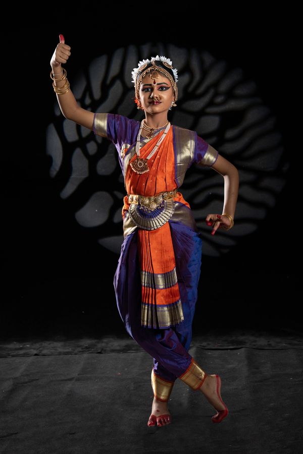 A classical Indian dancer in vibrant traditional attire performing a graceful pose.