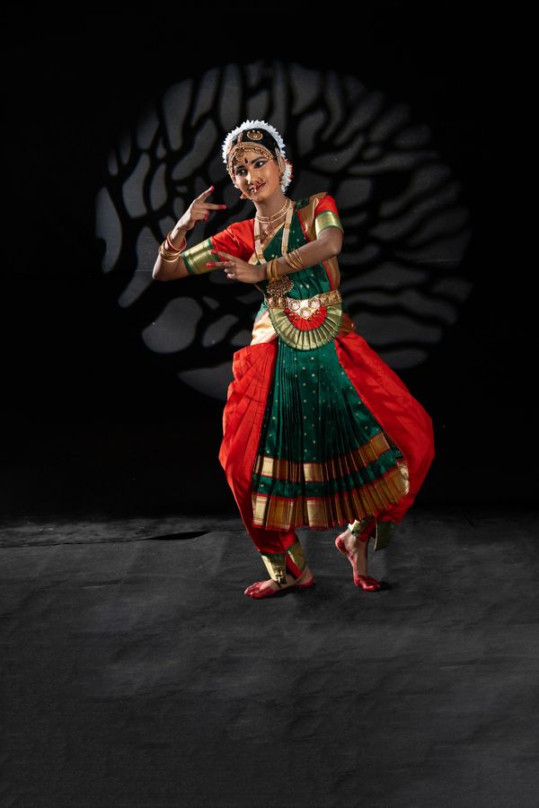 Indian classical dancer in traditional attire performing on stage.
