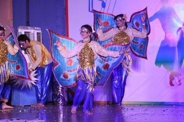 Performers in colorful butterfly costumes dancing on stage.