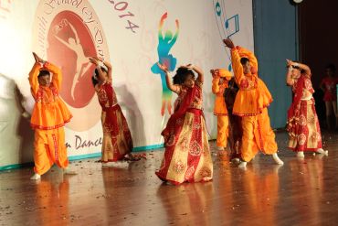 Children performing a traditional dance on stage.