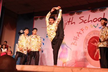 Man performing a high kick on stage with observers.