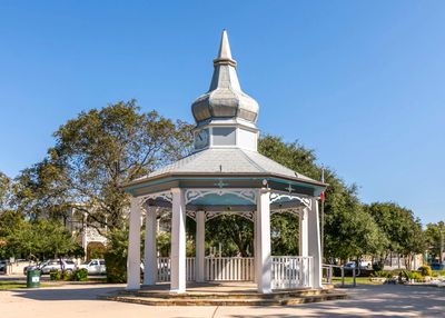 White gazebo with pointed roof in a sunny park.