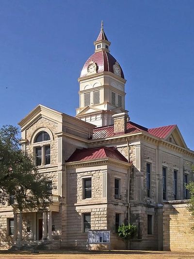 Historic courthouse with stone walls and clock tower under a clear blue sky.