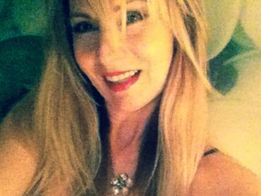 Smiling woman with long blonde hair and a necklace.