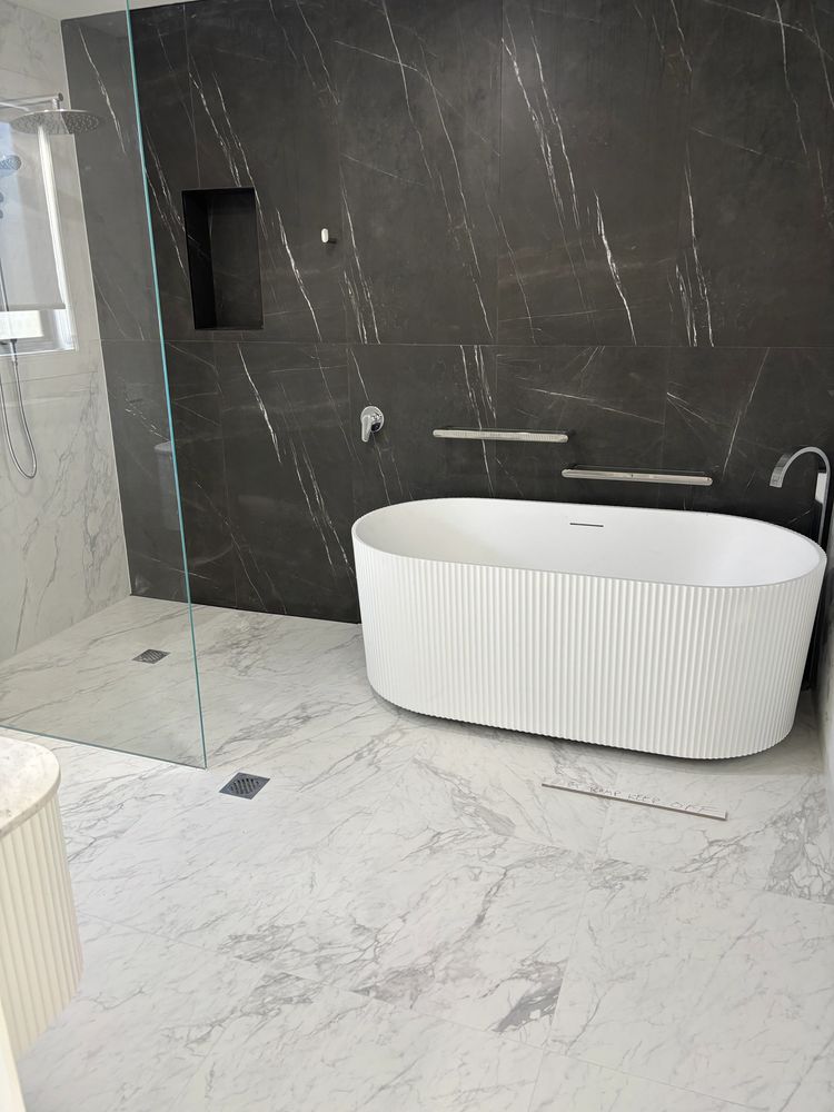 Modern bathroom with black marble wall and white bathtub.