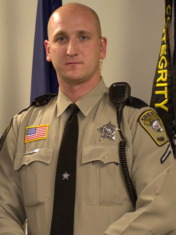 A serious sheriff in uniform with badges and radio.
