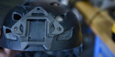 Close-up of a black tactical helmet with mounting points.