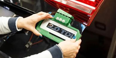 Person attaching a 2.0 TDI badge to a car's rear.