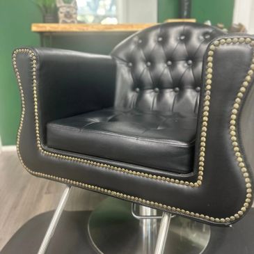 Black leather barber chair with studded detailing and metal base.