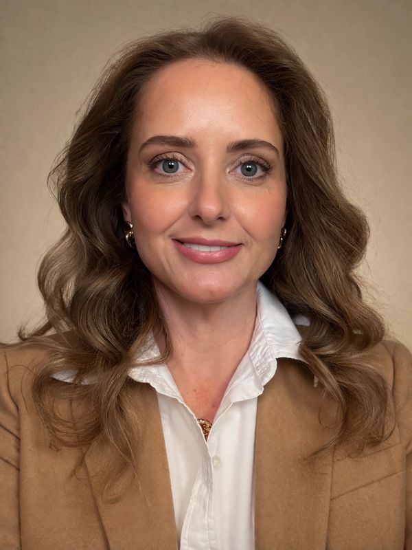 Professional headshot of Aron Yellott in a khaki blazer and white button down