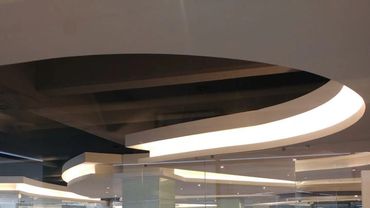 Modern ceiling design with curved light fixtures in a commercial space.