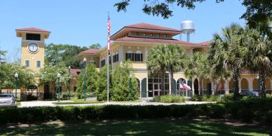 Historic yellow building with a clock tower and flags.