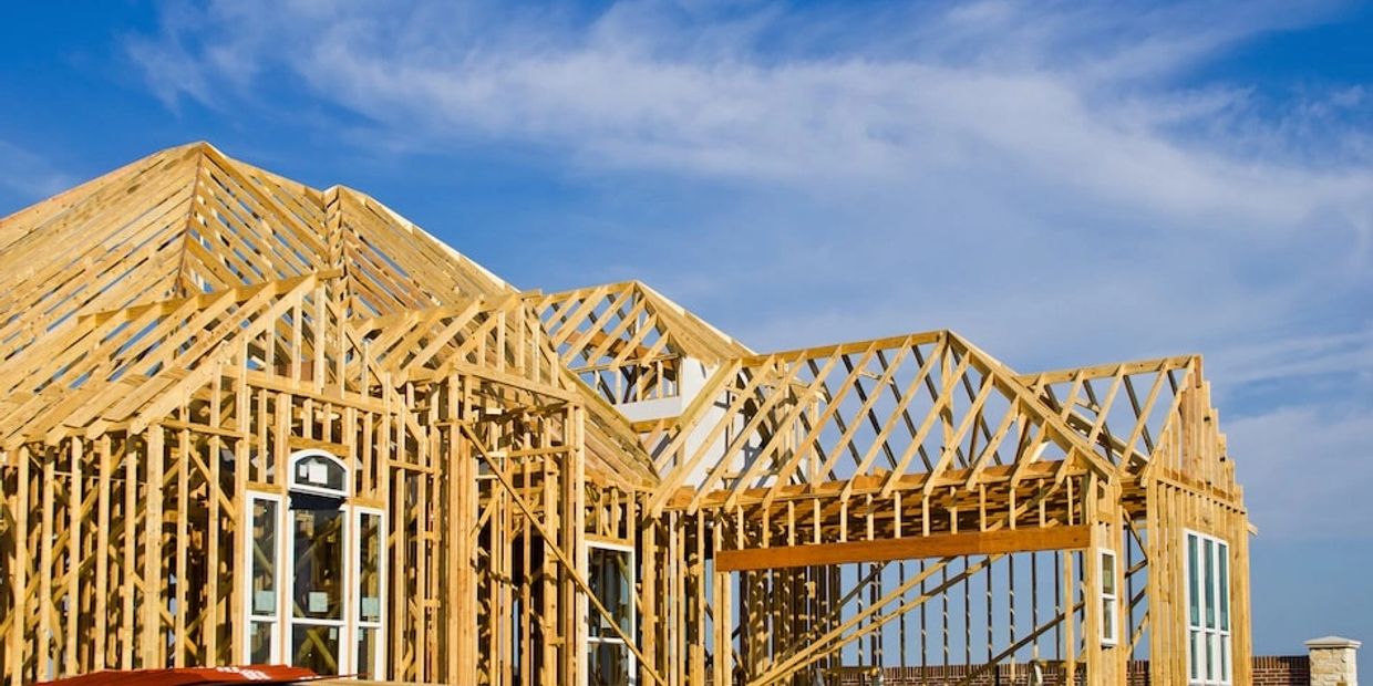 Wooden frame of a house under construction against a blue sky.
