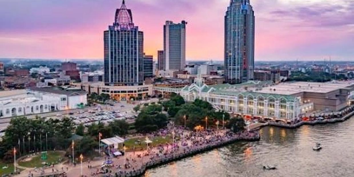 City skyline at sunset with waterfront and crowds.