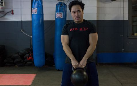 Man lifts kettlebell to waist level.