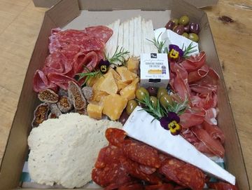 A charcuterie board with assorted cheeses, meats, olives, and crackers.
