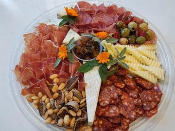 A vibrant charcuterie platter with meats, cheeses, nuts, and olives.