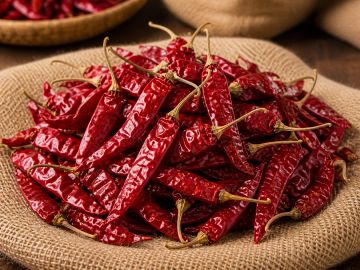 A pile of dried red chili peppers on a burlap cloth.