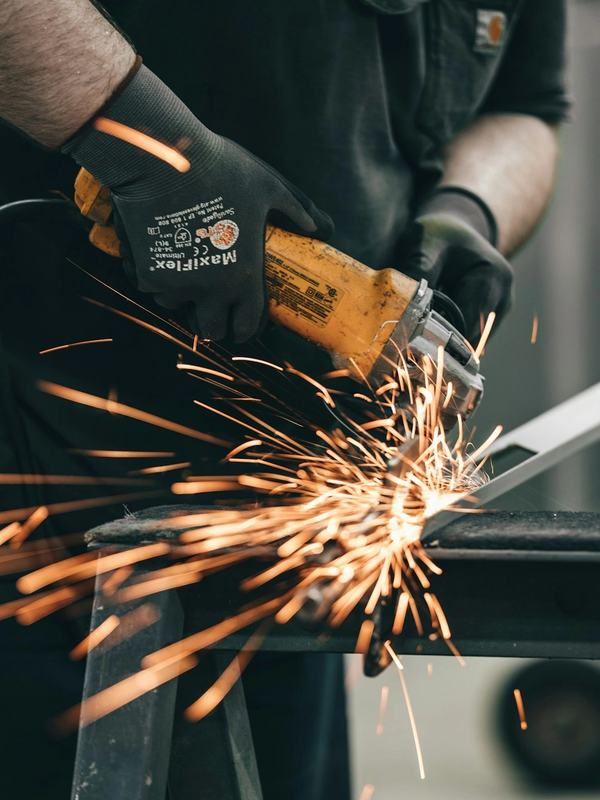 Worker using an angle grinder, sparks flying.