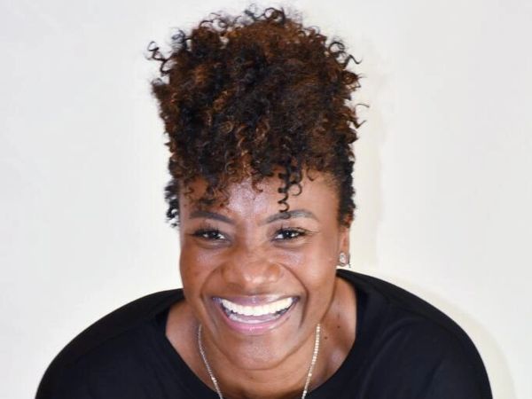 Smiling woman with curly hair and black top.