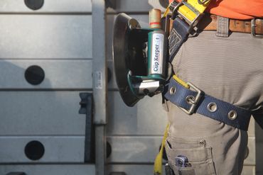 Man wearing a harness with the cup keeper suction cup holder attached to his toolbelt.
