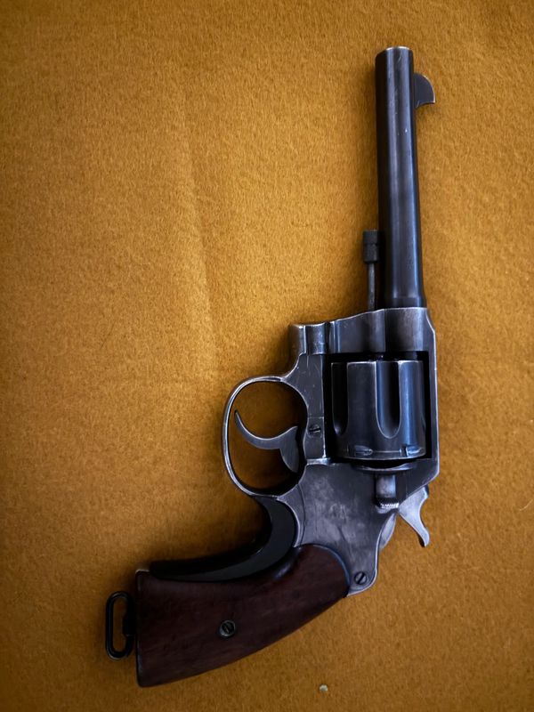 Vintage revolver with wooden grip on a brown surface.