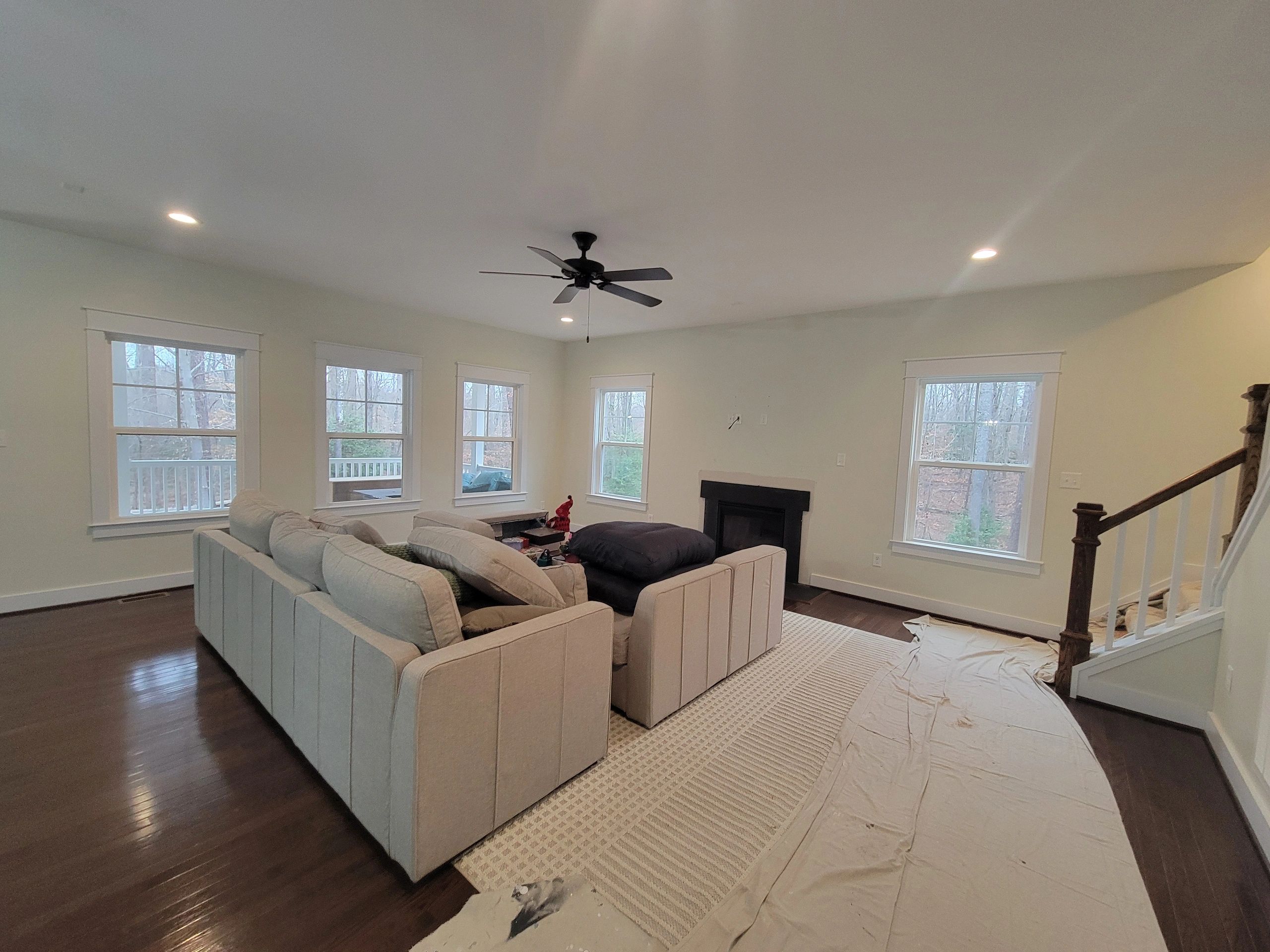 Spacious living room with beige sofas, large windows, and dark hardwood floors.