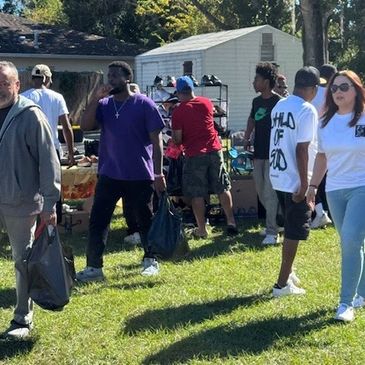 People shopping at an outdoor yard sale on a sunny day.