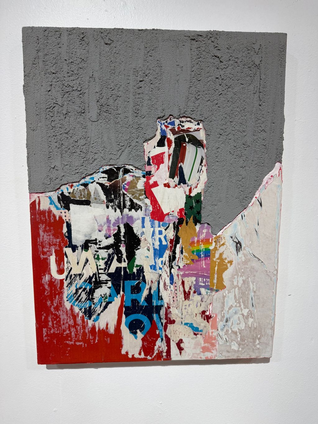 Abstract textured wall art with gray, red, and colorful torn paper layers.
