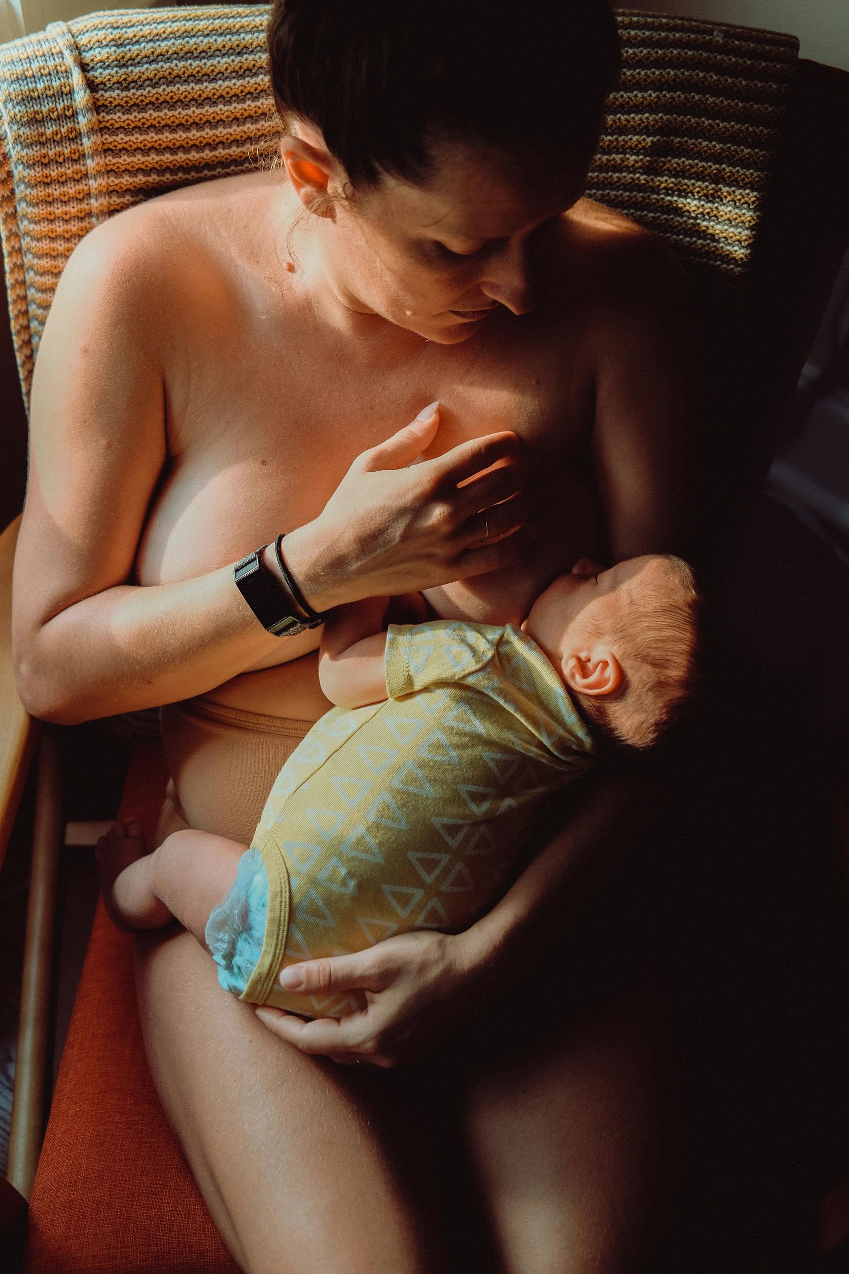 Mother breastfeeding her newborn calmly with the support of her postpartum doula in Durham Region