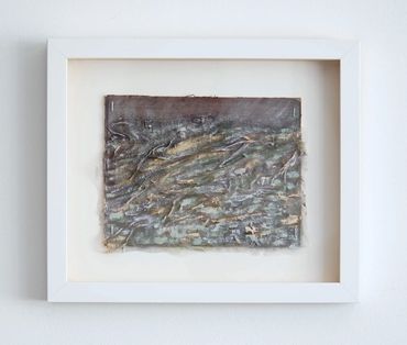 Abstract textured artwork in a white frame on a wall.