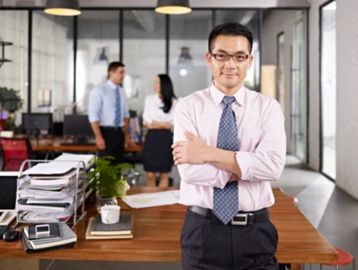 Confident businessman standing with folded arms in modern office.