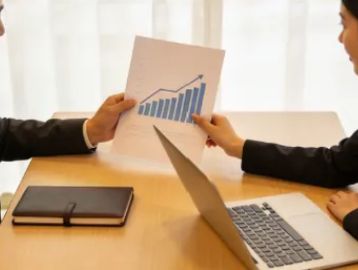 Two professionals reviewing a positive growth chart at a meeting.