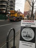 Street scene with a danger sign about men working above.
