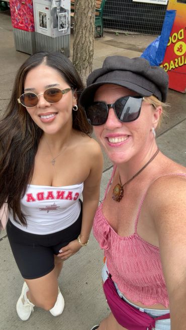 Two women smiling outdoors, wearing sunglasses.