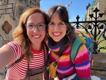 Two smiling women posing for a selfie outdoors on a sunny day.