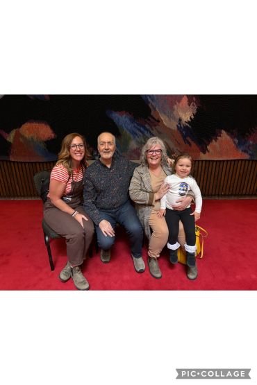 Family sitting together on a red carpet.