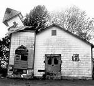 Old, dilapidated house with a leaning tower in black and white.