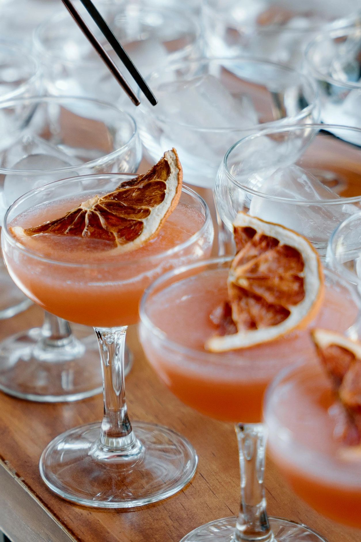 Cocktails garnished with dried citrus slices in elegant glasses on a wooden surface.
