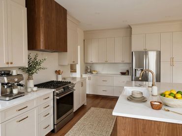 Modern kitchen with white cabinets, wooden accents, and stainless steel appliances.