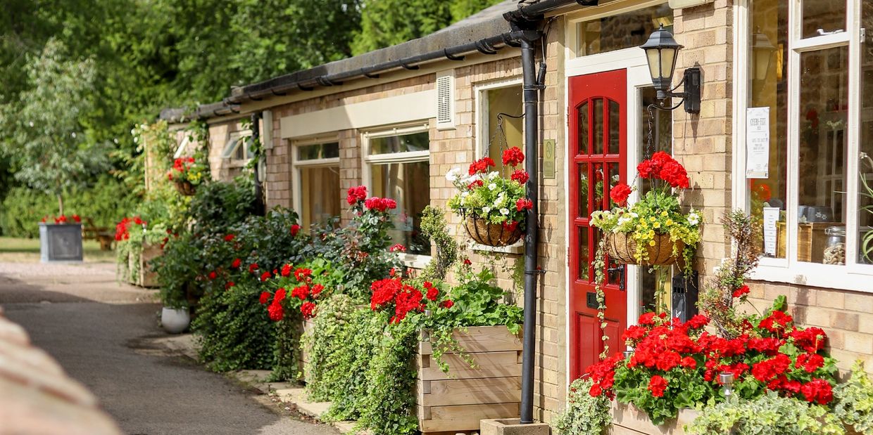 Charming brick house with red door and vibrant flower planters along the pathway.