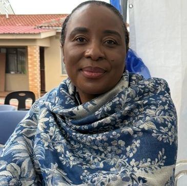 Woman wrapped in a blue floral shawl smiling gently.