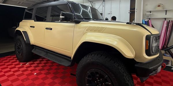 A beige SUV parked in a garage with hexagonal ceiling lights and a red checkered floor.