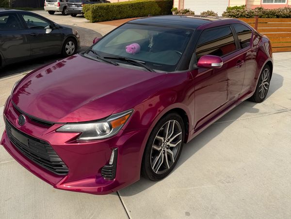 Shiny purple sedan parked in a suburban driveway on a clear day.