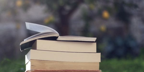 Stack of books with one open on top in an outdoor setting.