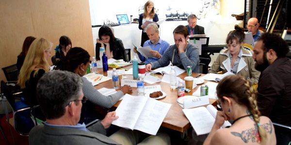 Group reading and discussing scripts around a table.