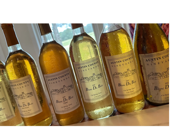 Bottles of Austin County Vineyards Blanc Du Bois wine from various years.